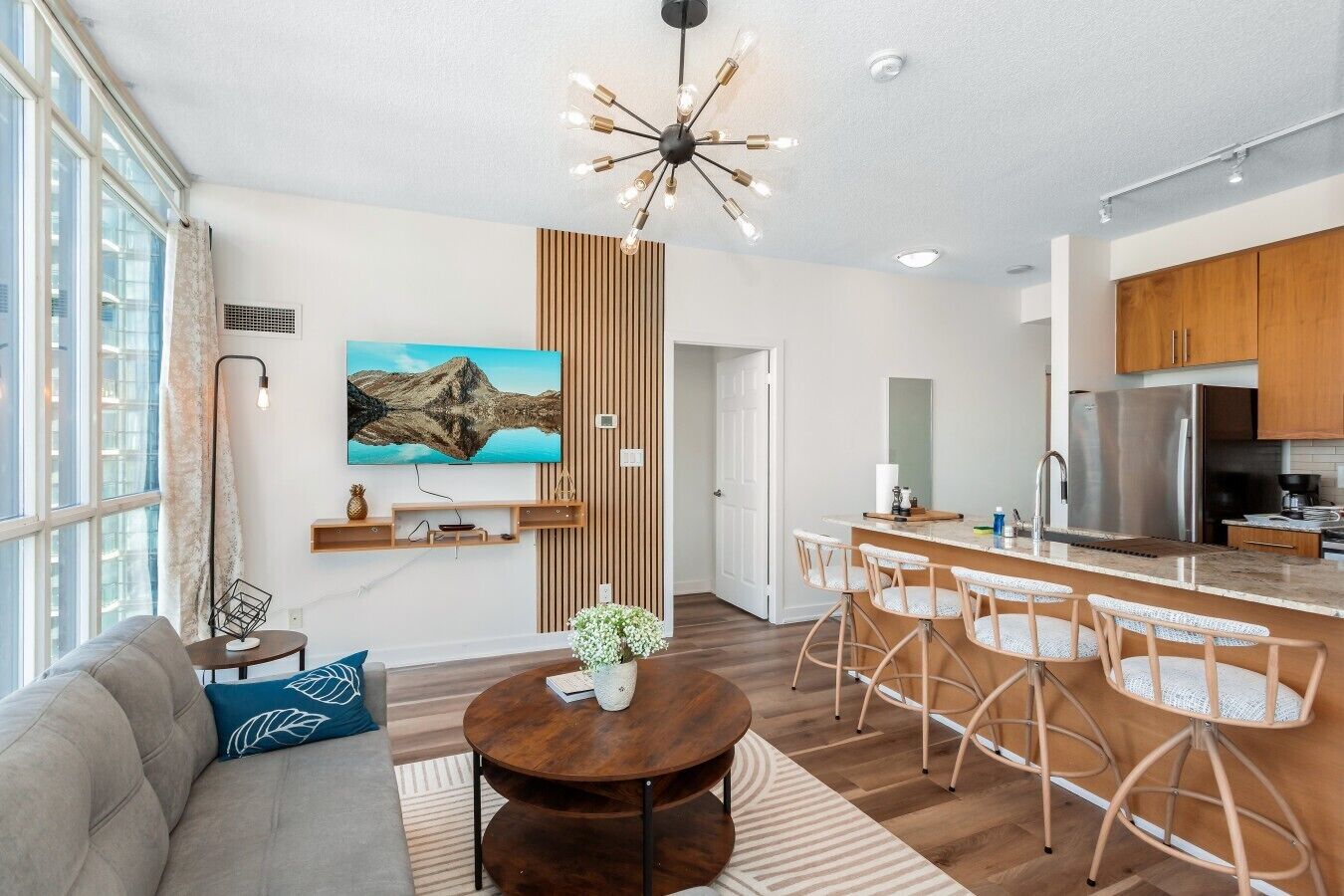 A modern living room with a sofa, a round coffee table, and a TV mounted on the wall.
