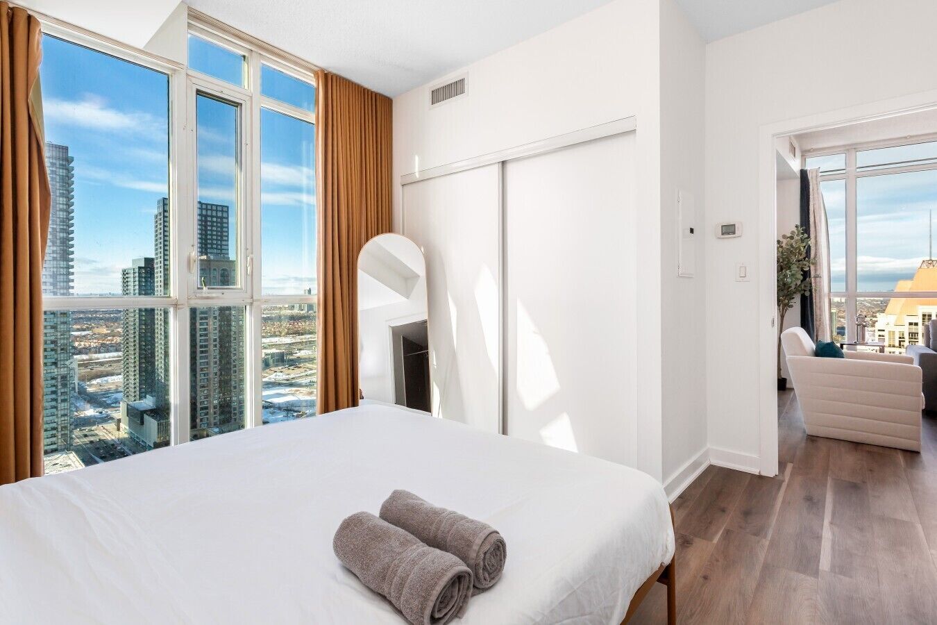 A hotel room with a large bed, a view of the city, and a seating area.