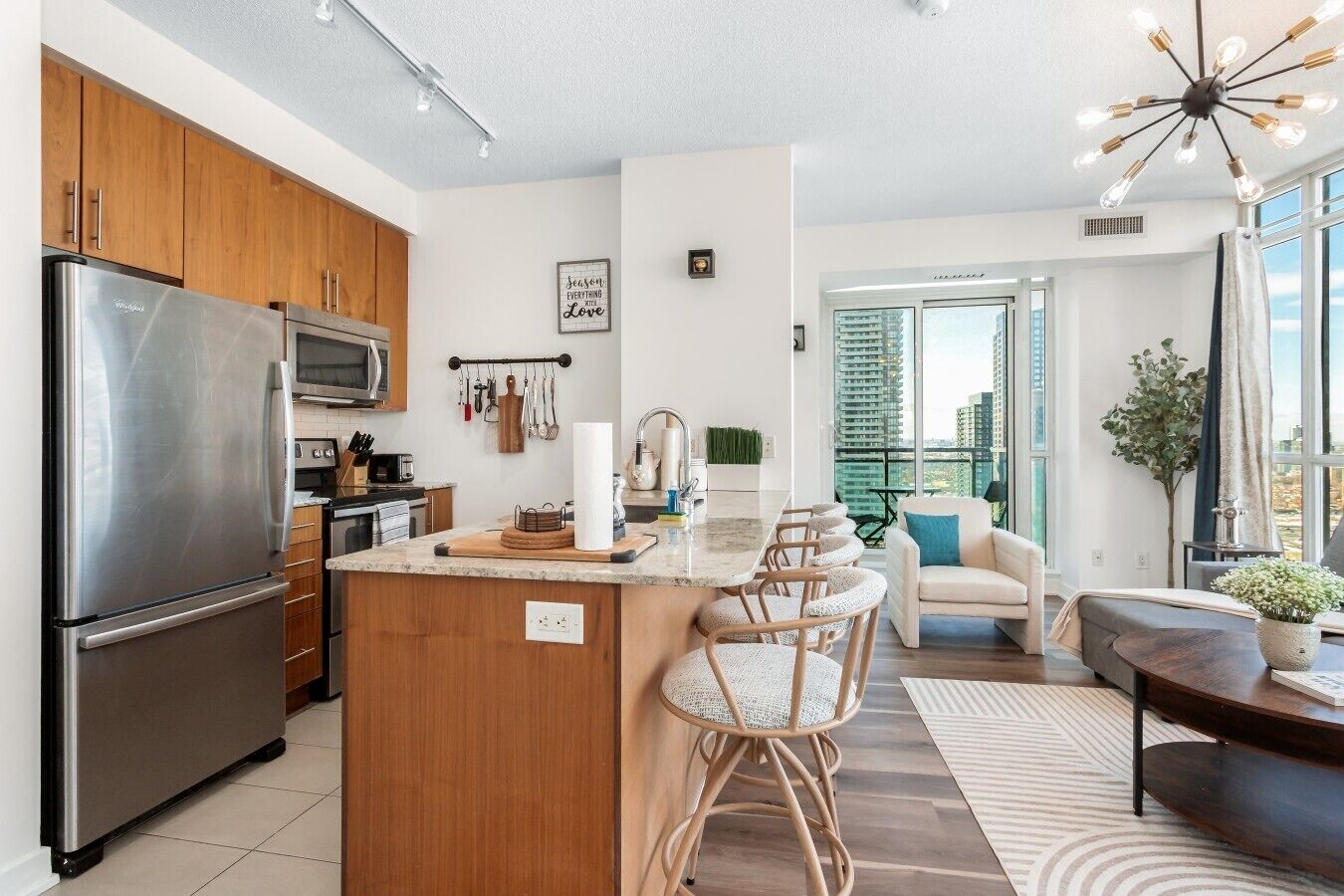 A modern kitchen with a stainless steel refrigerator, wooden cabinets, and a central island with bar stools.