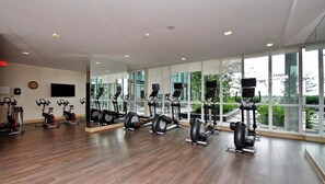 Une salle de sport équipée d’appareils de cardio, de miroirs et de grandes fenêtres.