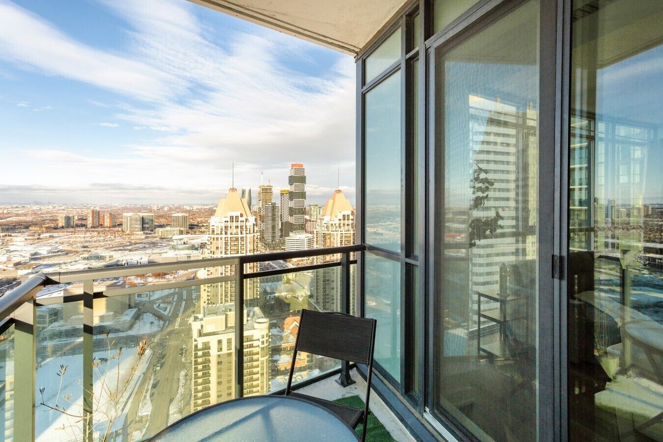 Un immeuble de grande hauteur offrant une vue sur le paysage urbain, une chaise et une rambarde en verre.