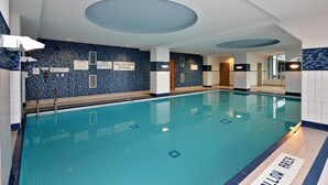 Ein Hallenbad mit gefliesten Wänden und Decke, gut sichtbarer Beschilderung und einem gefliesten Boden.