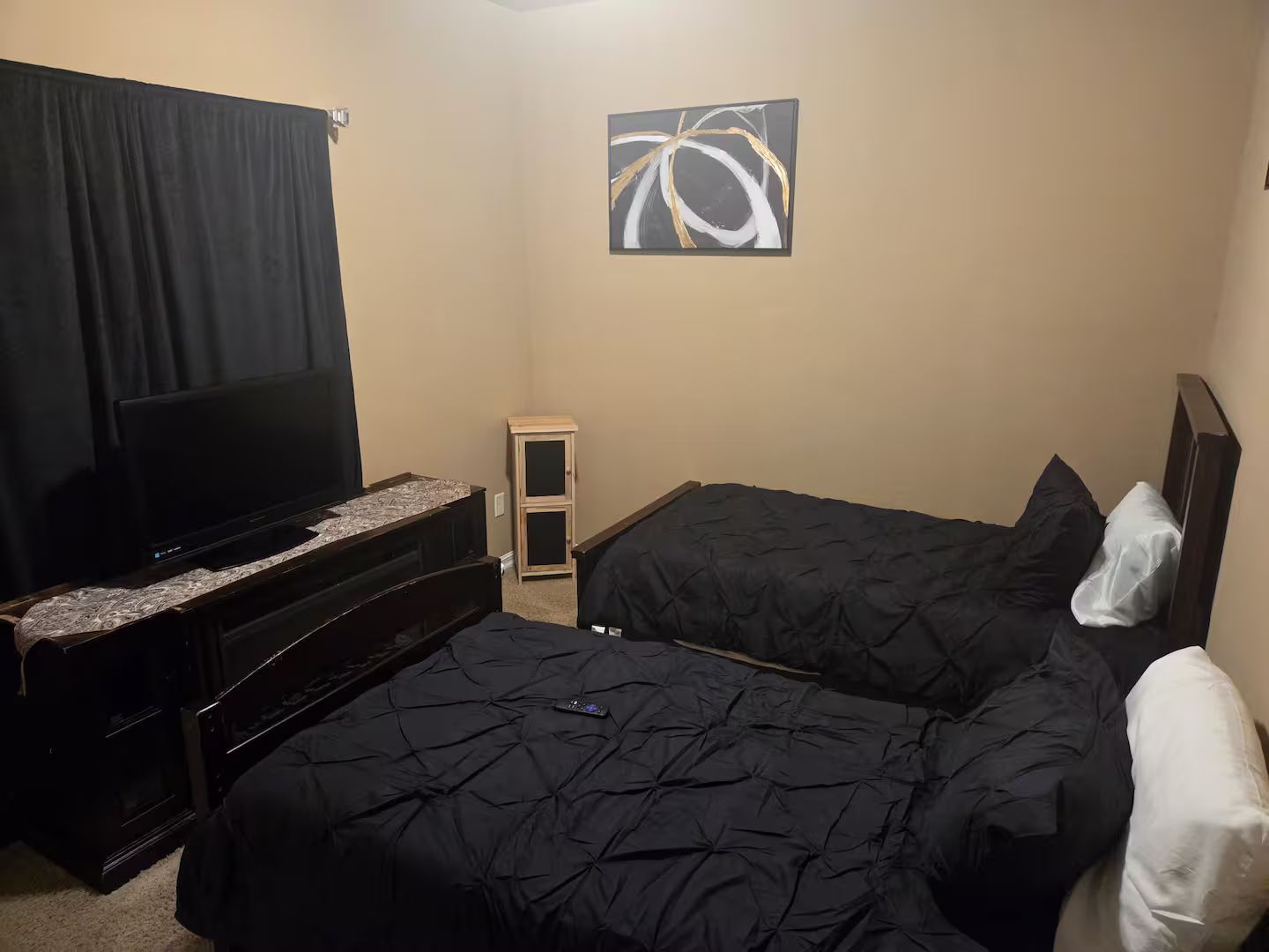 Ein Hotelzimmer mit einem Bett, einem Fernseher, einem kleinen Schrank und einem Gemälde an der Wand.