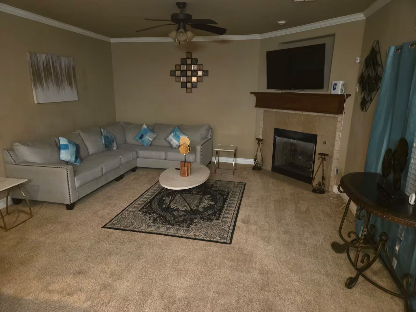 Ein Wohnzimmer mit Ecksofa, Kamin, Flachbildfernseher und Deckenventilator.