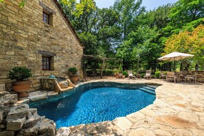 A stone building with a swimming pool, surrounded by trees and outdoor furniture. - A historic 3-story estate with a pool, sleeps 10 (Fredericksburg)