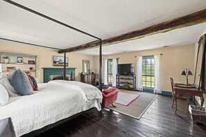 Een slaapkamer met een hemelbed, een televisie en een open haard.