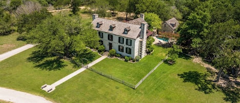 Une grande maison à deux étages, dotée d’une pelouse bien entretenue et d’une piscine.