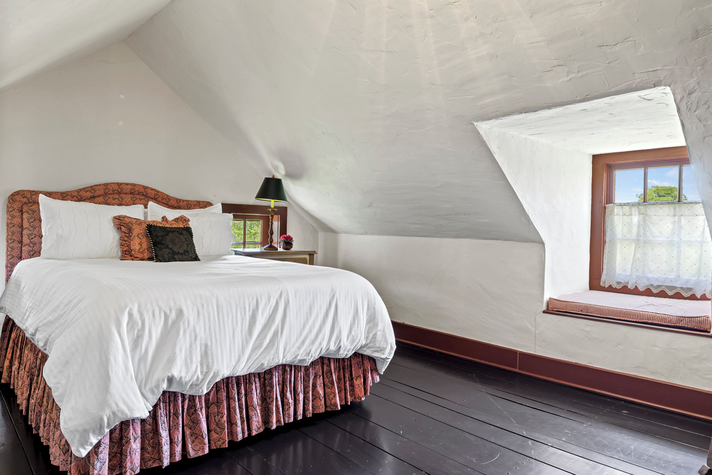 A bedroom with a large bed, a window with a view, and a wooden floor.