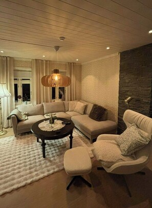 A modern living room with a sectional sofa, a round coffee table, and a unique pendant light.
