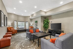 A modern living room with a sofa set, a coffee table, a flat-screen TV, and a large plant.