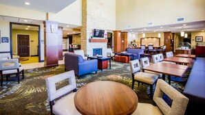 A hotel lobby with a fireplace, seating areas, and a bar.