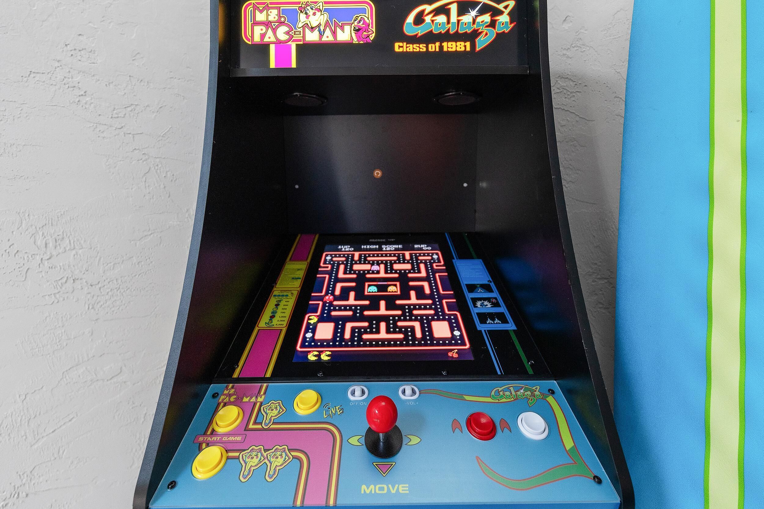 A Pac-Man arcade machine with a colorful maze game displayed on the screen.