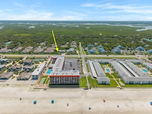 An aerial view of a coastal hotel with multiple buildings, a beach, and a marina. - Beachy Dreams NSB (New Smyrna Beach)