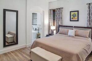 A bedroom with a large bed, a bedside table, a mirror, and a door leading to a bathroom. - Miami Lakes Retreat Heated Pool & Kids Play Area (Hialeah)