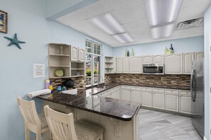 Een moderne keuken met witte kastjes, een granieten aanrecht en een roestvrijstalen koelkast.