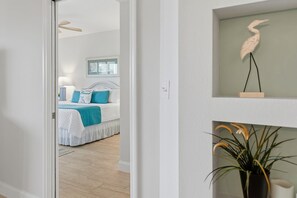 A bedroom with a bed, a bedside table, and a wall-mounted shelf with a decorative item. - Oceanwalk 15-503 (New Smyrna Beach)