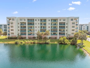 A multi-story hotel with balconies, a swimming pool, and a well-maintained lawn. - Oceanwalk 15-503 (New Smyrna Beach)