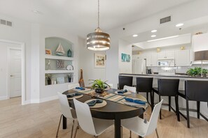 Een moderne keuken met witte kasten, een centraal eiland en een eethoek met een ronde tafel en stoelen.