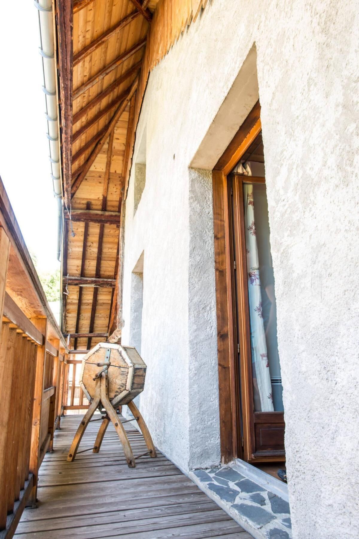 Une terrasse en bois mène à un bâtiment à l’extérieur blanc et doté d’une porte en bois.