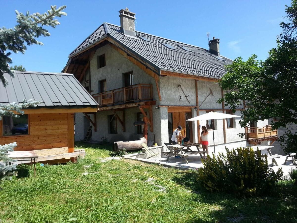 Un chalet rústico con balcón, terraza de madera y zona de estar al aire libre.