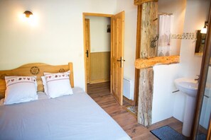 A bedroom with a wooden bed, a white wall, and a bathroom with a wooden door and white tiles. - Ground floor, terrace, balcony, tv, ski locker, 135m², Valloire (Valloire)