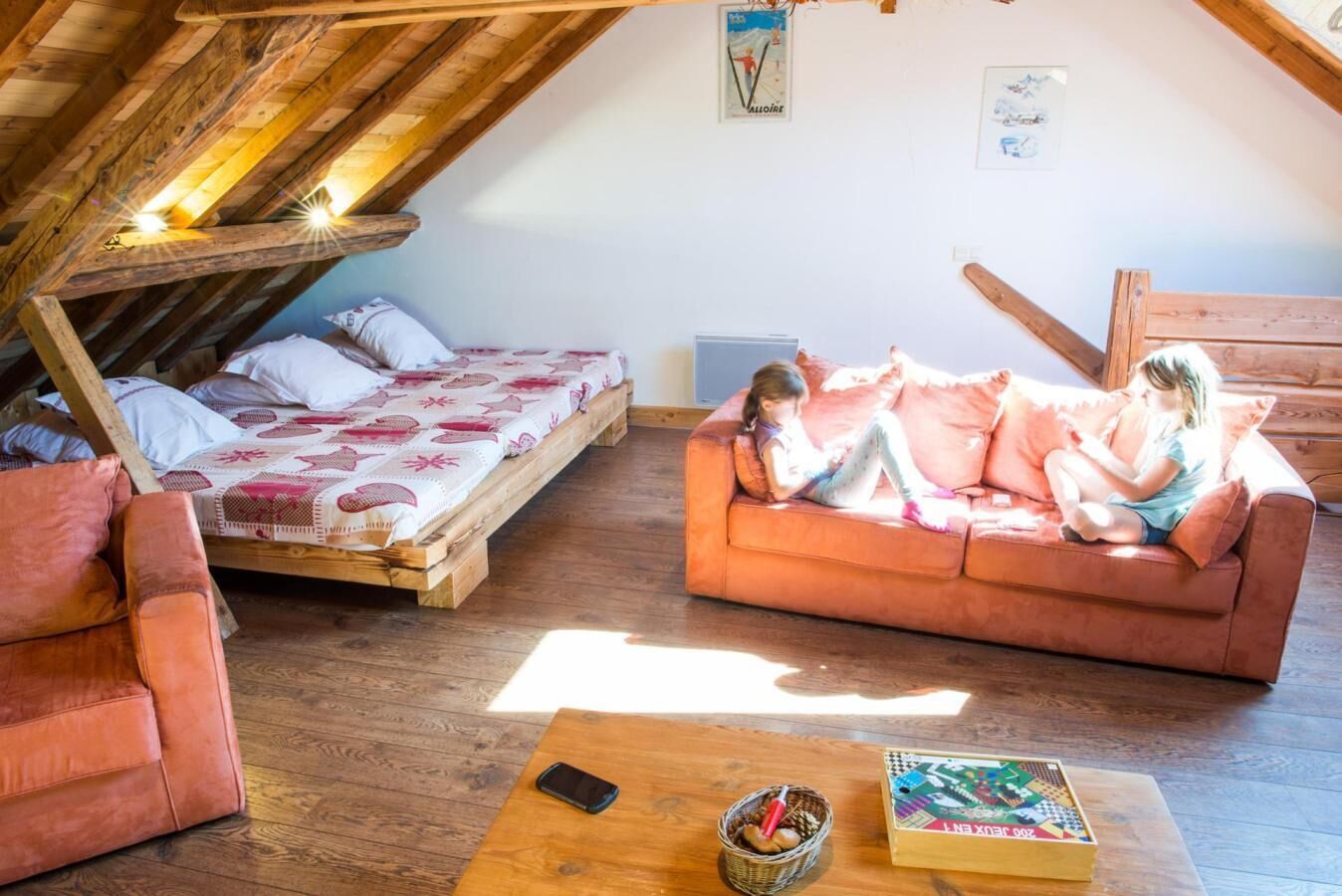 A room with a loft bed, a sofa, and a table with a book and a basket.