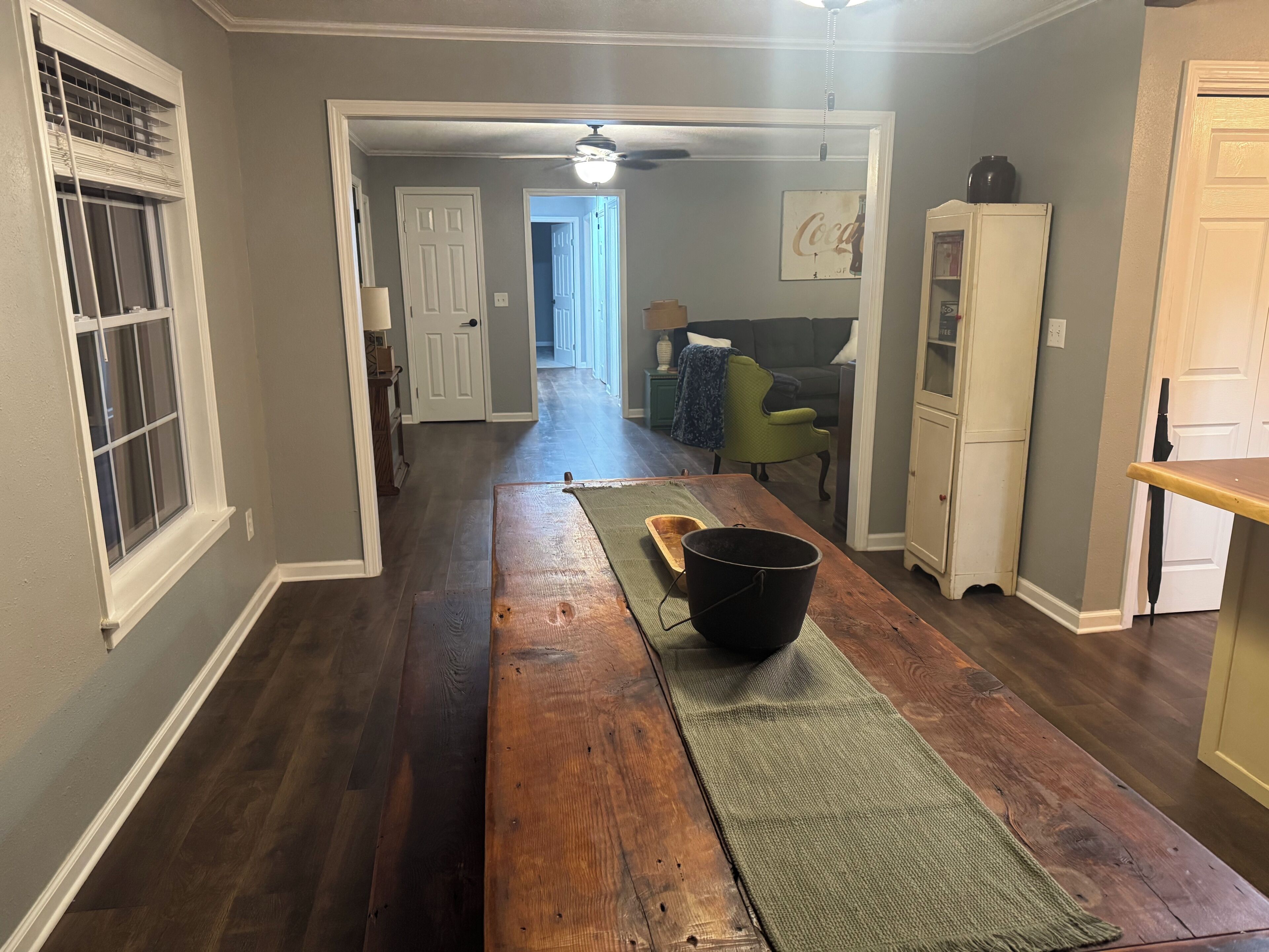A hallway with a wooden table, a black bucket, and a green mat. There is a door at the end of the hallway.