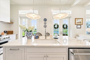 A kitchen with a large island, white cabinetry, and pendant lighting. - Seaside Cottage 101 YEA (Port Aransas)
