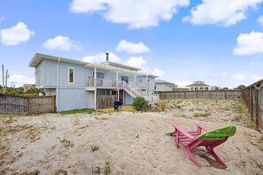 Une maison située en bord de mer, dotée d’un porche abrité et d’une cour sablonneuse.