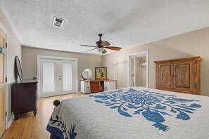 Ein Schlafzimmer mit einem großen Bett, einem Deckenventilator, einem Schminktisch, einem Schreibtisch und einem Kleiderschrank.