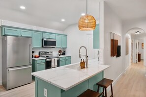 Une cuisine moderne avec des meubles de couleur turquoise, des appareils en acier inoxydable et un îlot central en marbre.