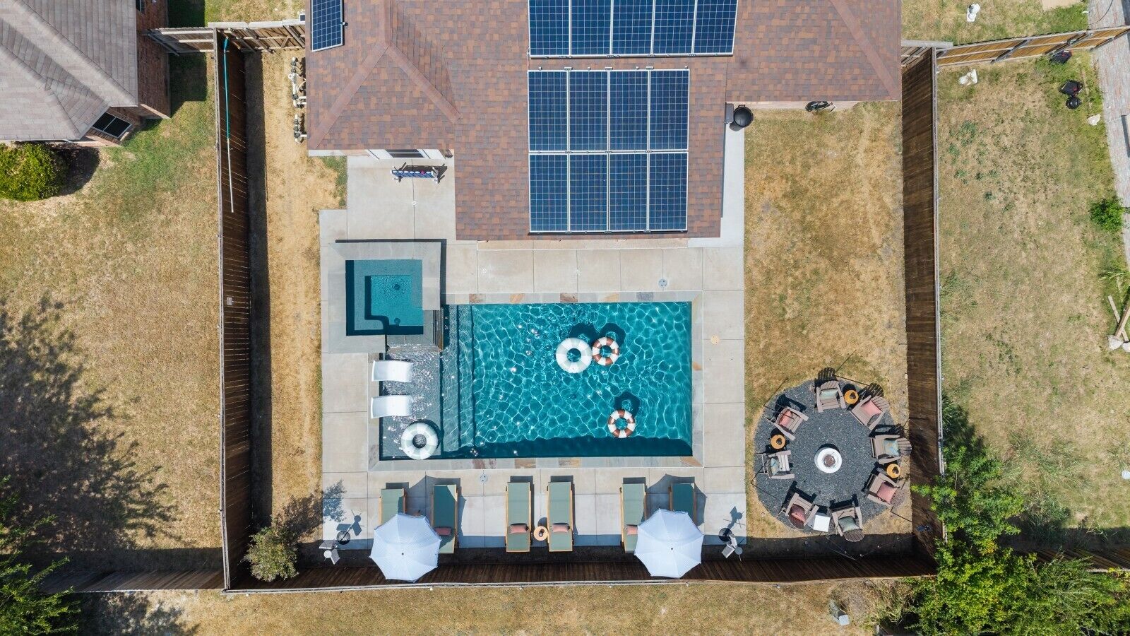 A rooftop swimming pool with a sun terrace, solar panels, and outdoor seating.