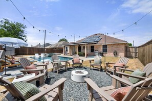Un jardin avec une piscine, un espace salon extérieur et un coin barbecue.