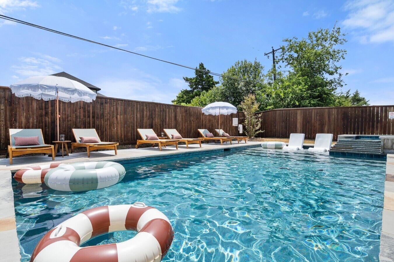 Une piscine avec des chaises longues et des parasols.