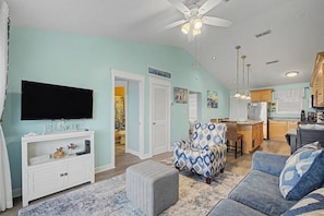 A living room with a television, a white entertainment unit, a patterned armchair, and a sofa. - Escape by the bay! Baywatch E10 (Pensacola Beach)