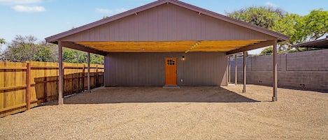 A covered outdoor area with a wooden door and a gravel floor.