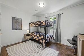 A bunk bed room with a desk, chair, and a poster on the wall. - 3-bedroom house in marvelous Mesa with refreshing AC (Mesa)