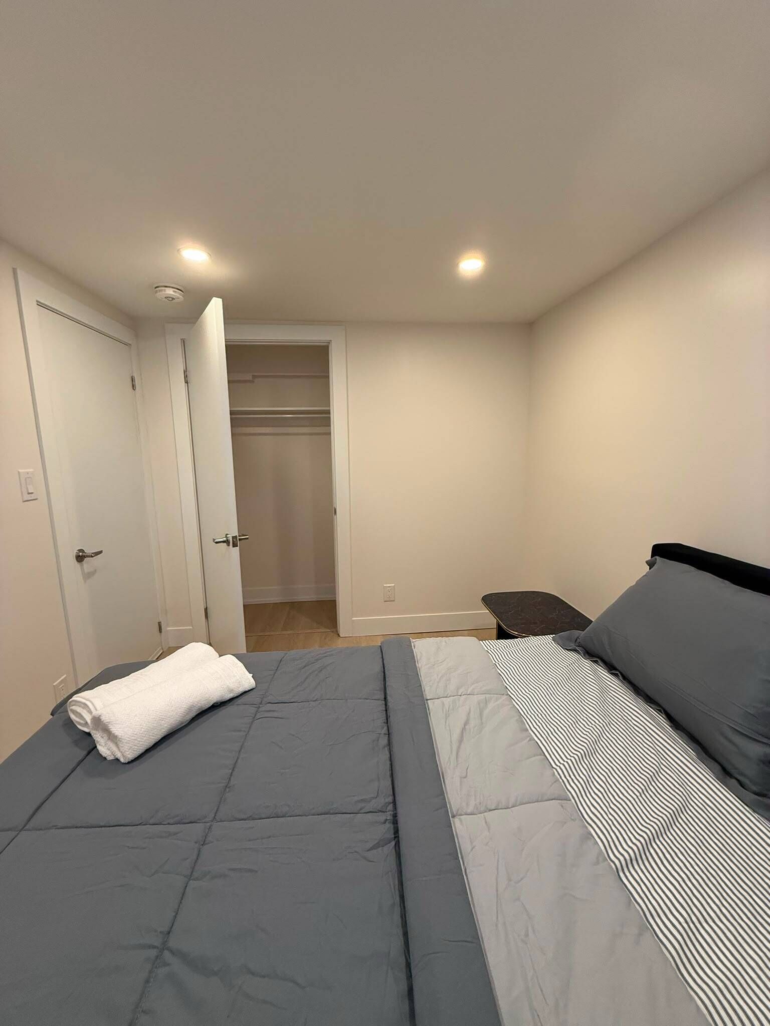 Une chambre à coucher avec un lit, une table de chevet, une chaise et une armoire.
