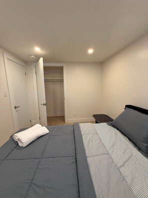 Ein Schlafzimmer mit Bett, Nachttisch, Sessel und Kleiderschrank.