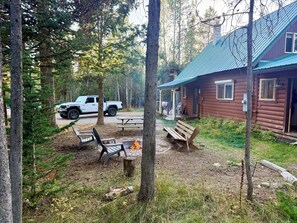 Eine Holzhütte mit Veranda, Picknicktischen und einer Feuerstelle.