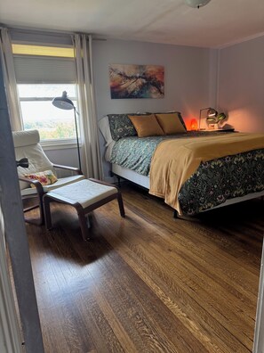 A bedroom with a bed, a chair, a desk with a laptop, a lamp, and a painting on the wall. - Peaceful Four-Bedroom Country Retreat with Hot Tub & InfraredSauna (Parkville)