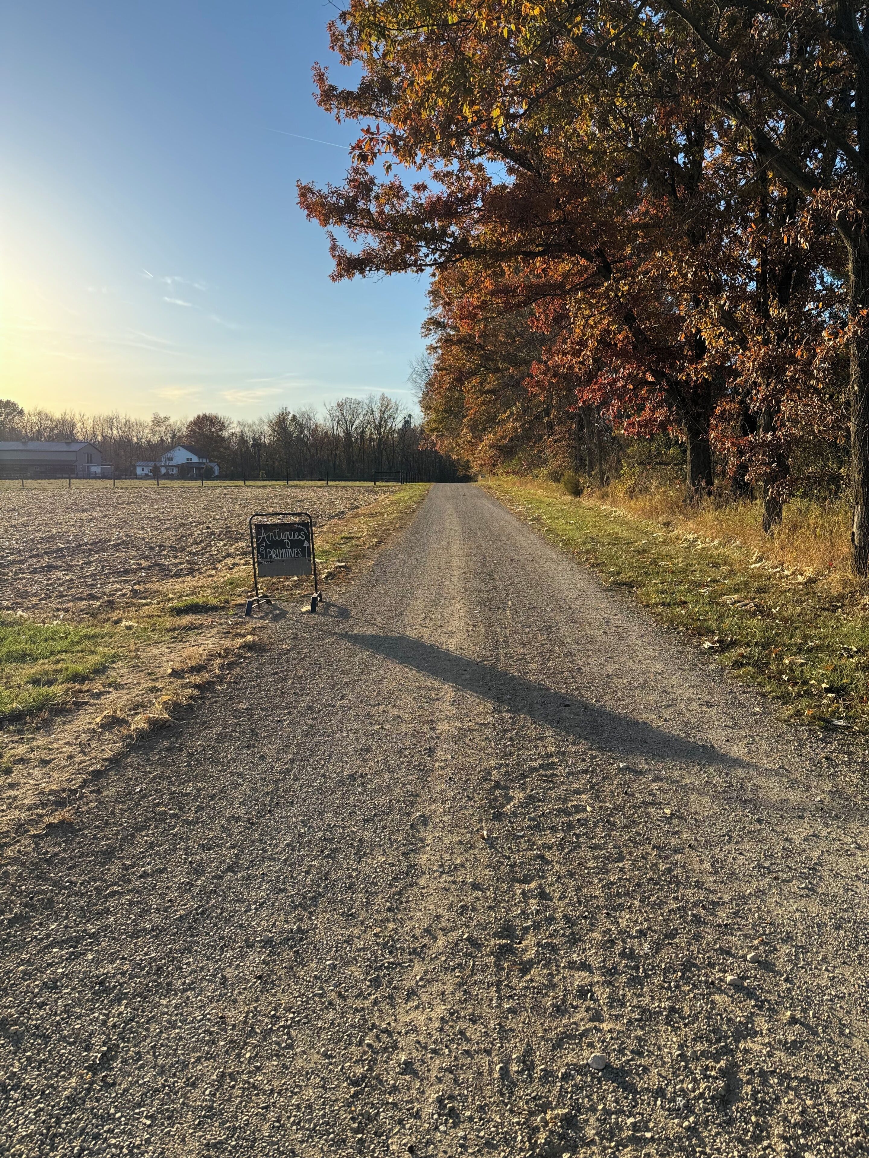 A gravel road with a sign indicating antiques and pottery.