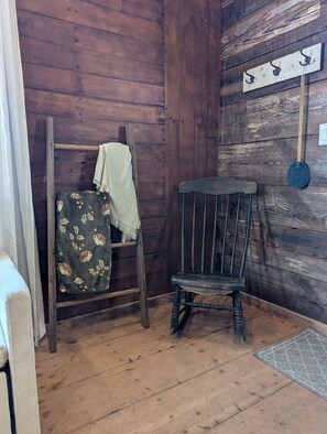 Een rustiek houten interieur met een houten stoel, een ladder en een kapstok aan de muur.