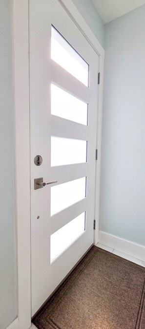 A white door with a keyhole and a handle, a doormat, and a carpeted floor. - Private Waterfront House • Private Dock • 2 Min Walk to Beach (Indian Shores)