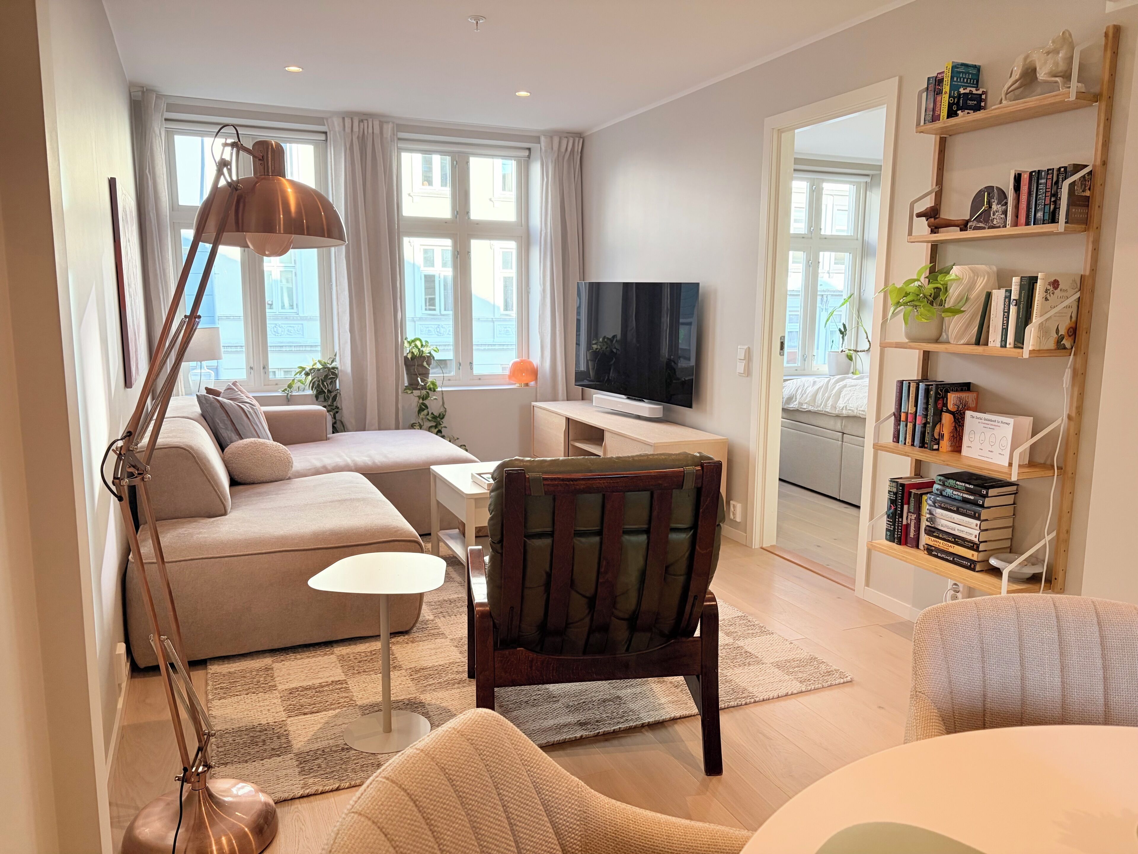 A modern living room with a sofa, a coffee table, a TV, and a bookshelf.