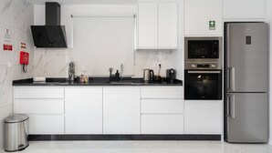 Una cocina moderna con armarios blancos, un refrigerador de acero inoxidable y un horno empotrado.