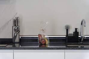A kitchen with a marble backsplash, a knife set, a bottle of olive oil, and a bag of snacks. - Branco's Apartment 03 by GALMI (Ponta do Sol)