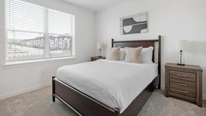 A bedroom with a large bed, two bedside tables, a window with blinds, and a wall-mounted artwork. - Landing | Stylish 1BD, Pool, Courtyard (Dallas)