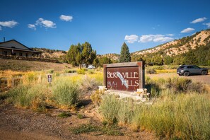 A sign for Berryville B.V.H. Hills with a building and vehicles in the background. - Stargazing Dome Climbing Wall Zion & Bryce (Glendale)
