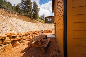 A patio with a wooden table and benches, surrounded by a stone wall. - Stargazing Dome Climbing Wall Zion & Bryce (Glendale)